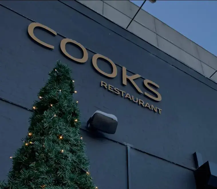 Indgang til Restaurant Cooks med facade og dekoreret træ.